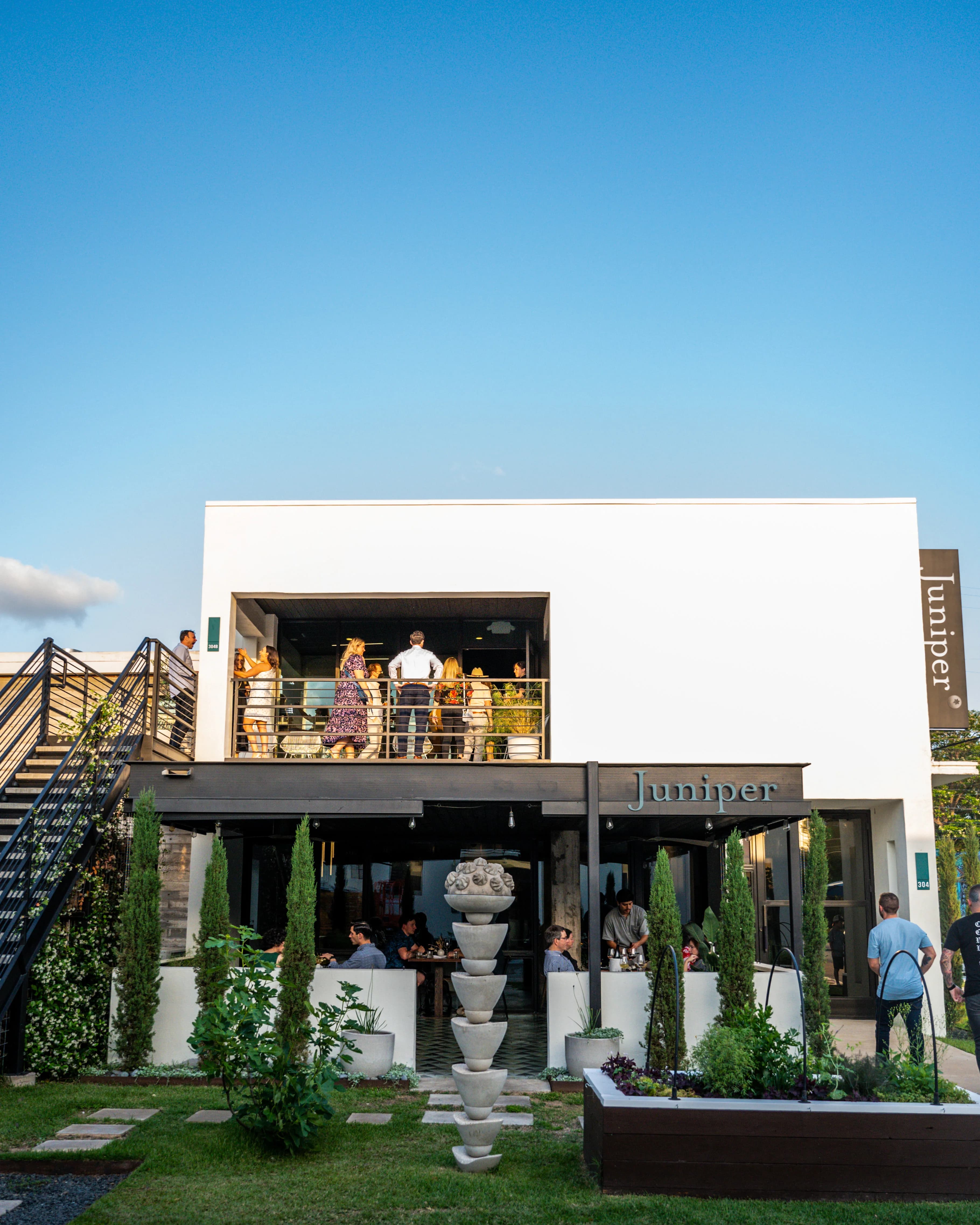 Juniper exterior at golden hour with guests gathered on the upstairs patio