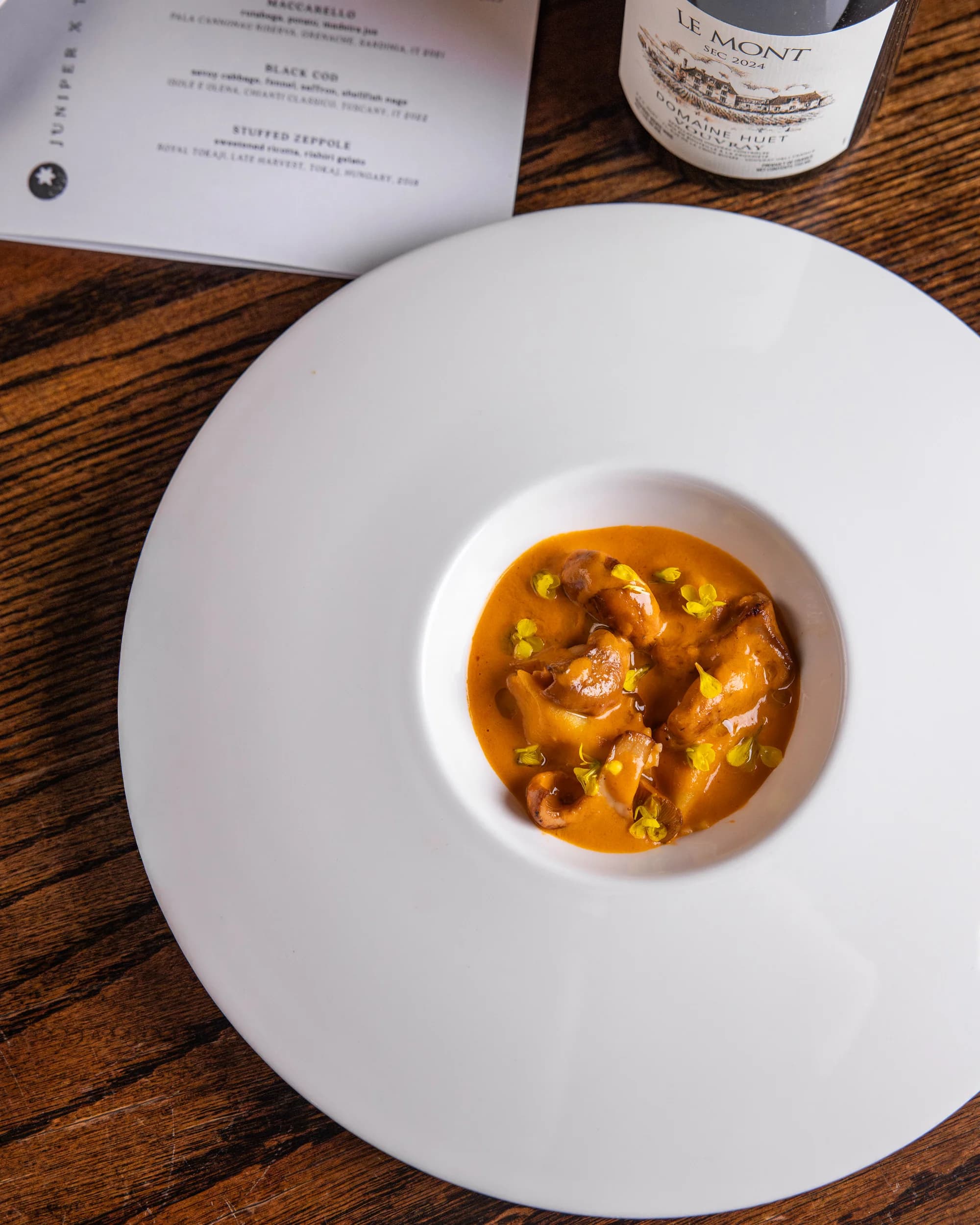 Tortellini in saffron cream with menu and wine bottle