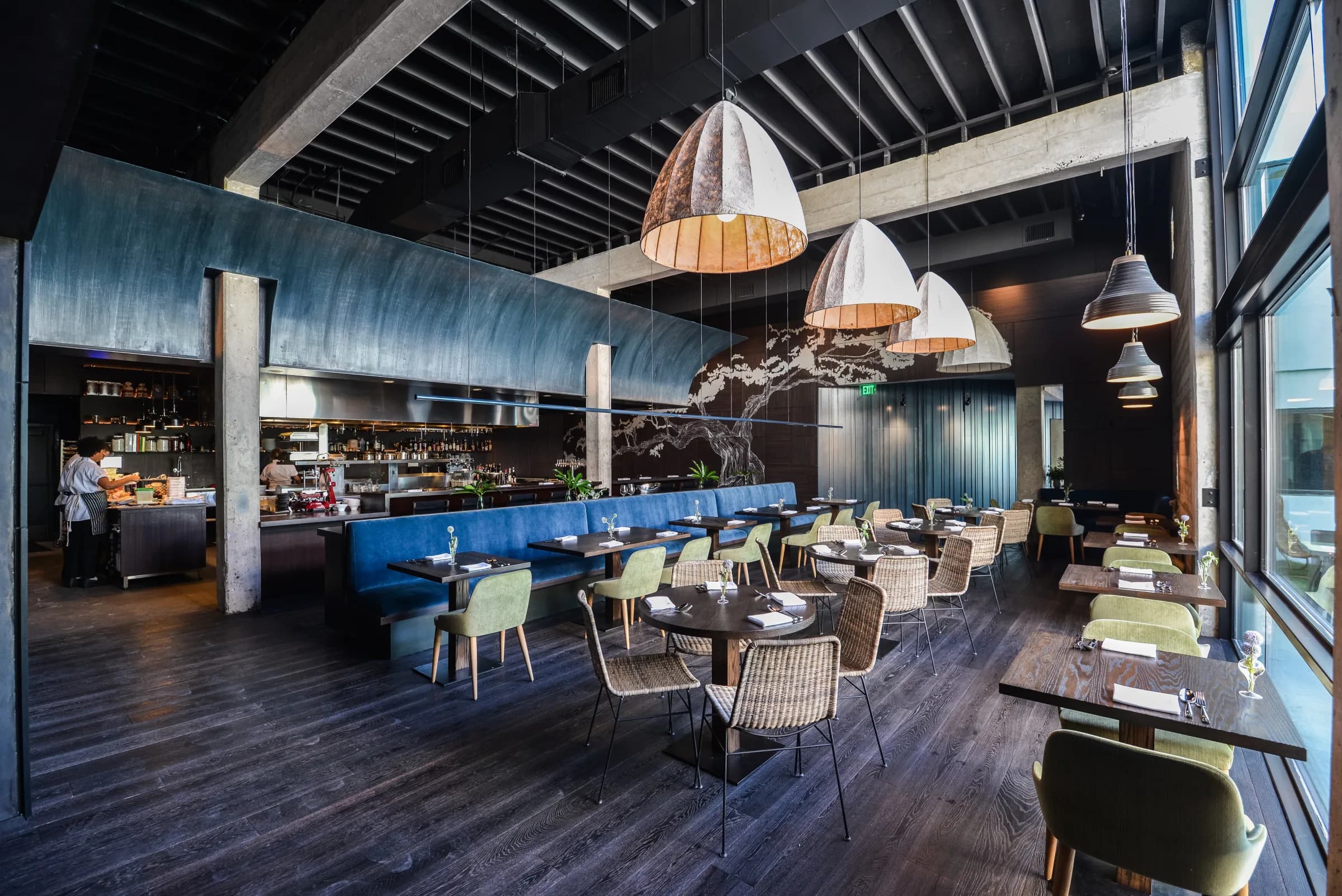 Juniper dining room with blue banquette, woven pendant lights and the open kitchen at the back