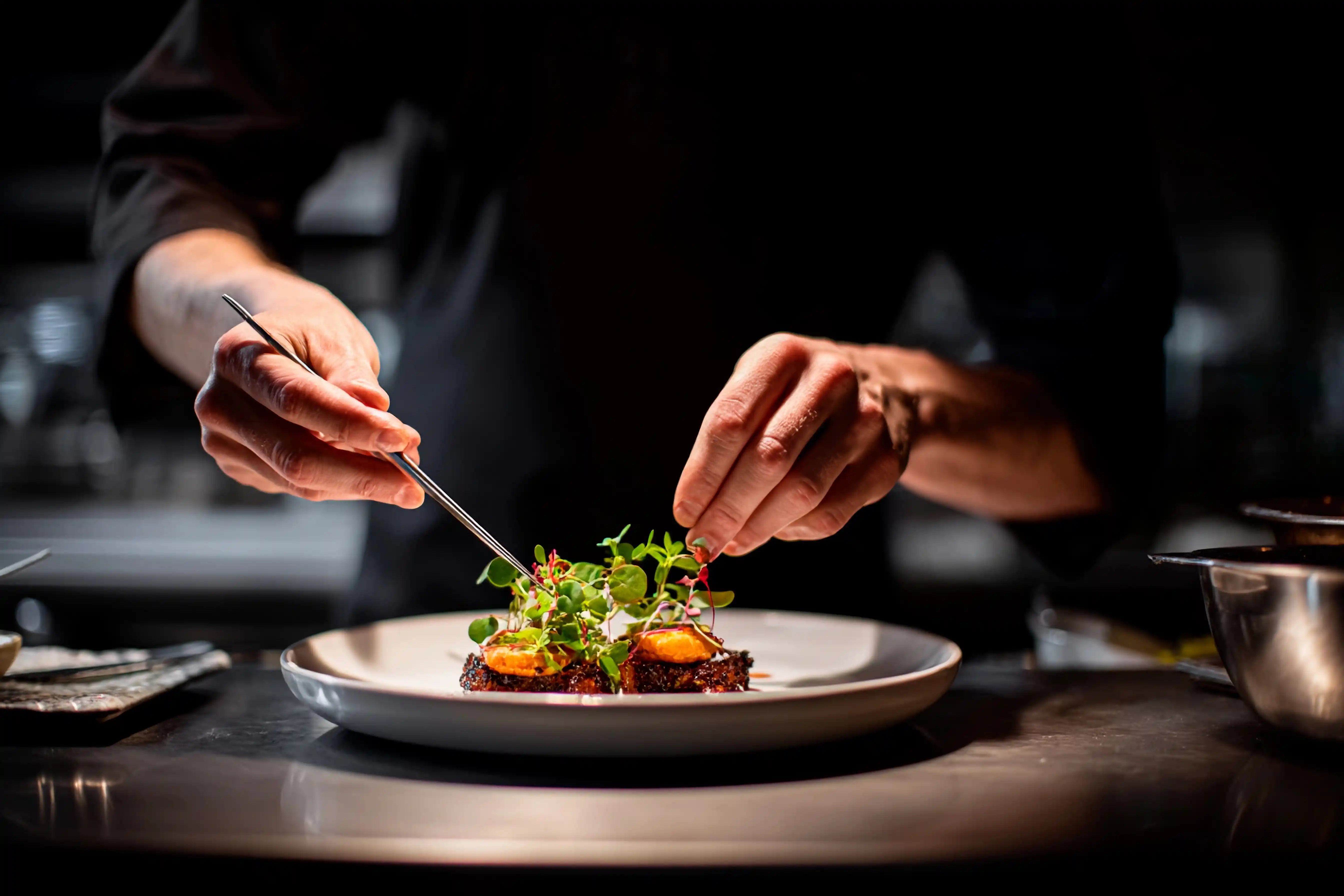 Chef finishing a plated dish in a professional kitchen